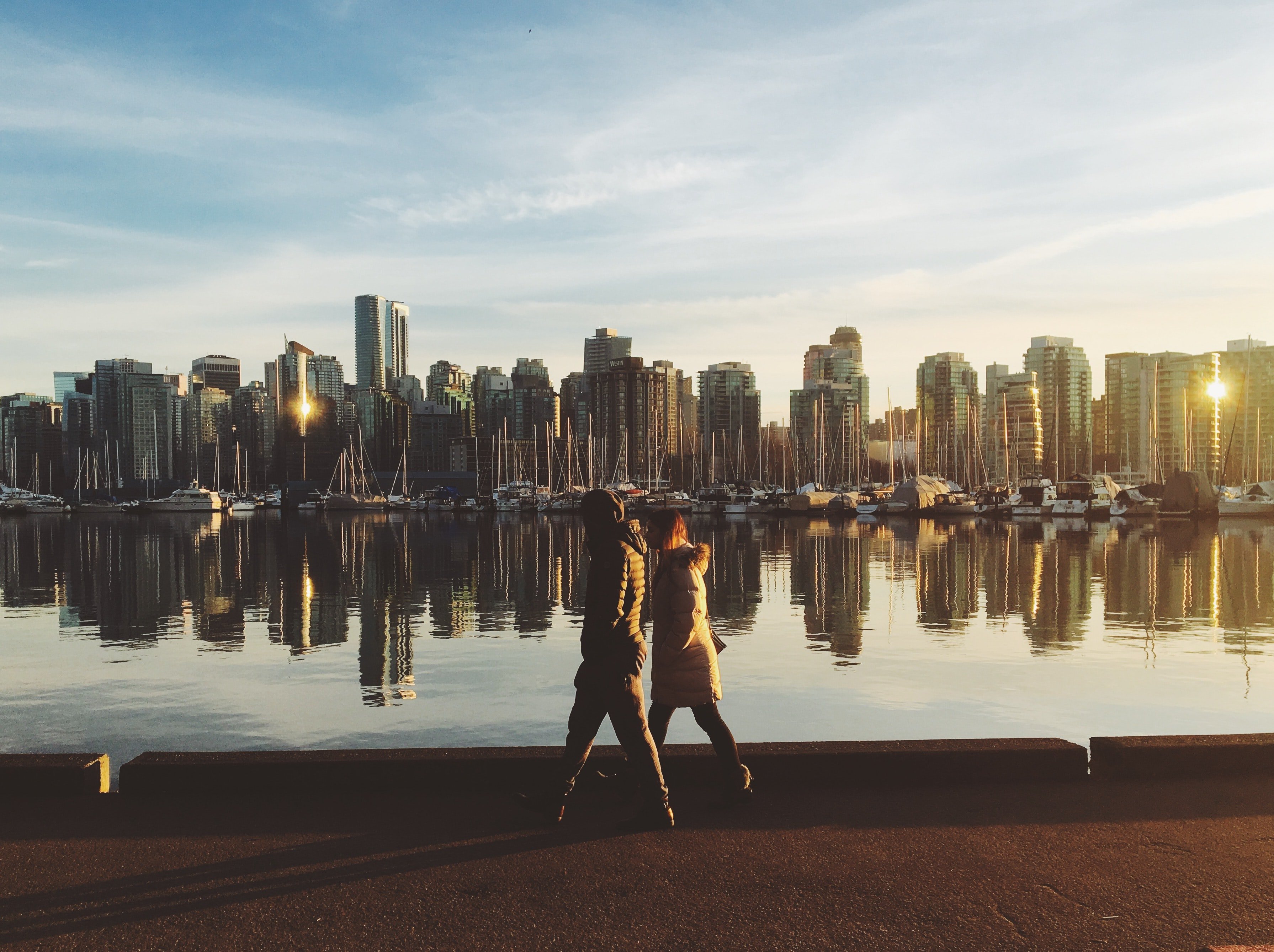 two people walking by river with city skyline